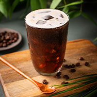 Vaso con cerveza de café sobre una tabla de madera
